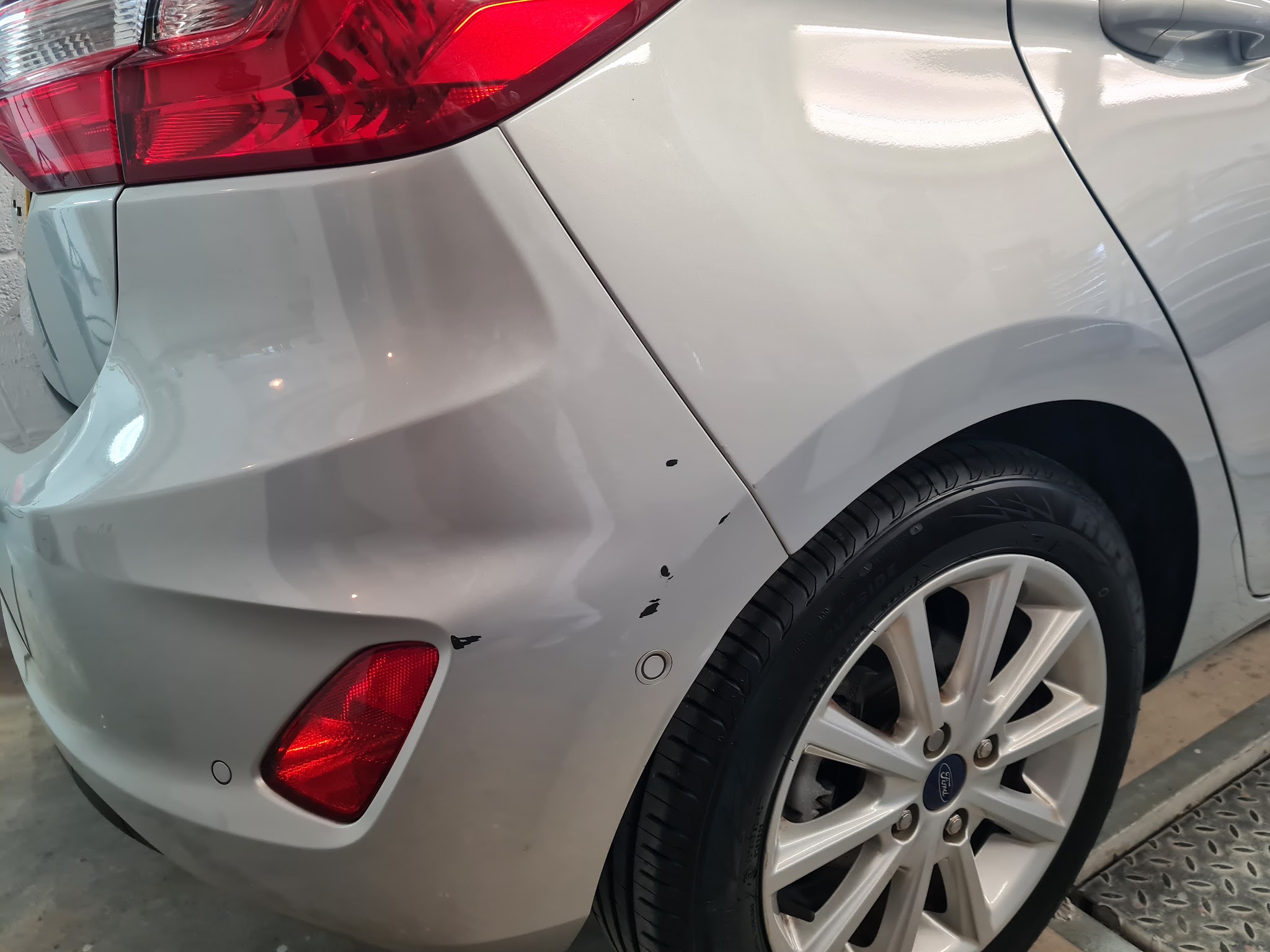 Silver Ford Fiesta with a dent in the rear corner above the reflector