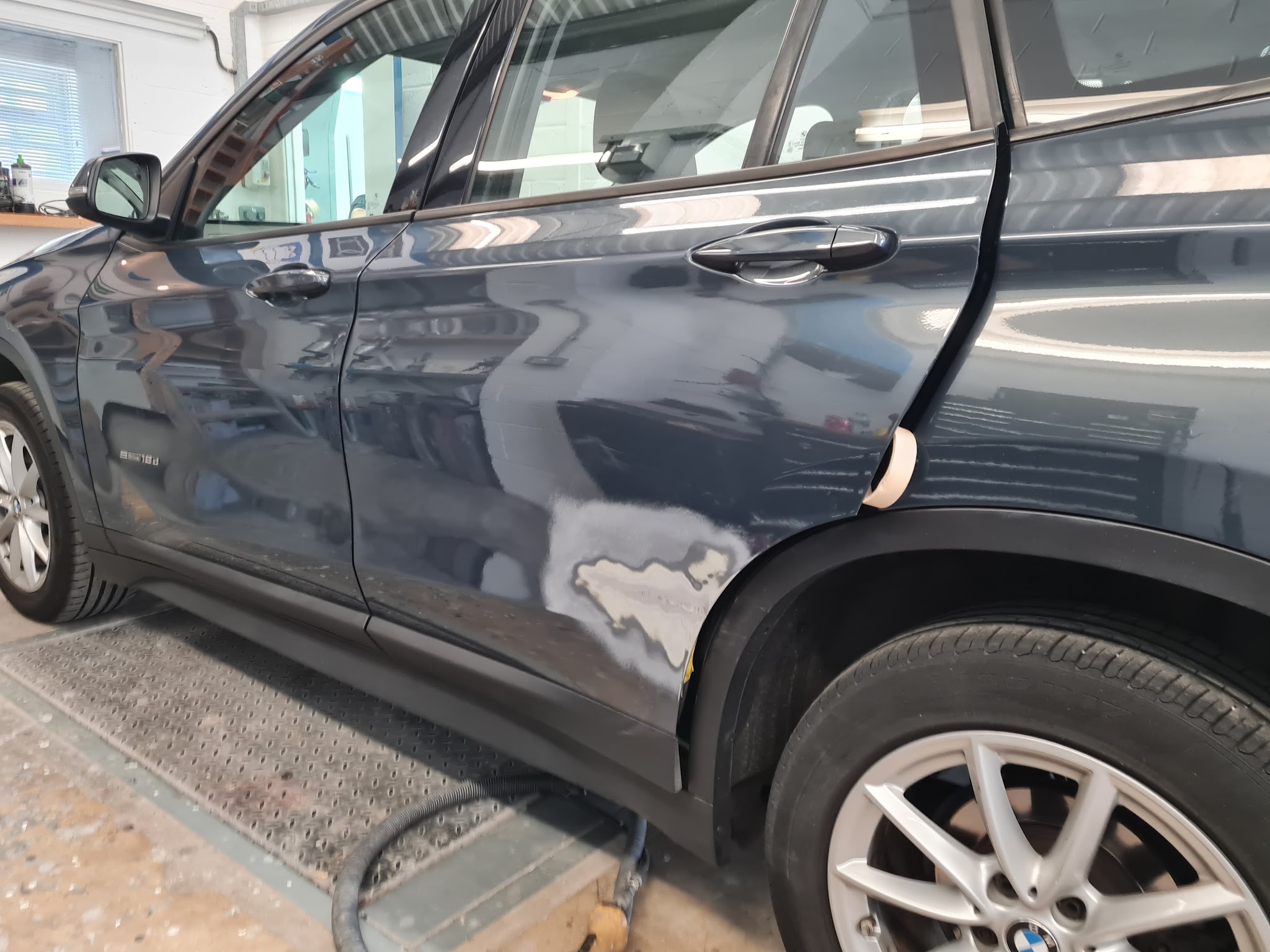 Dark BMW with the rear door and arch dented and partly prepared