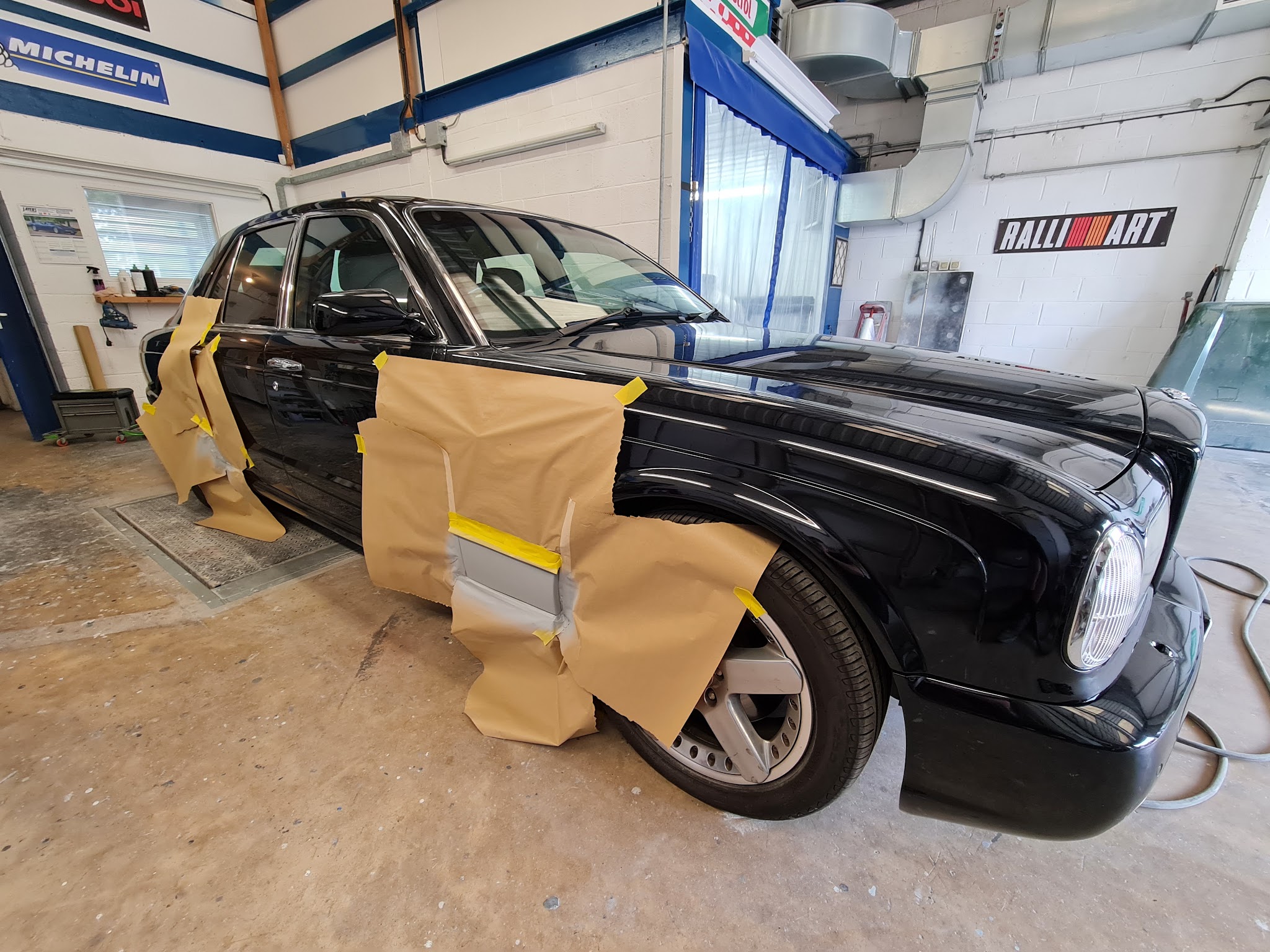 Black classic saloon masked with brown paper around the front wing and door