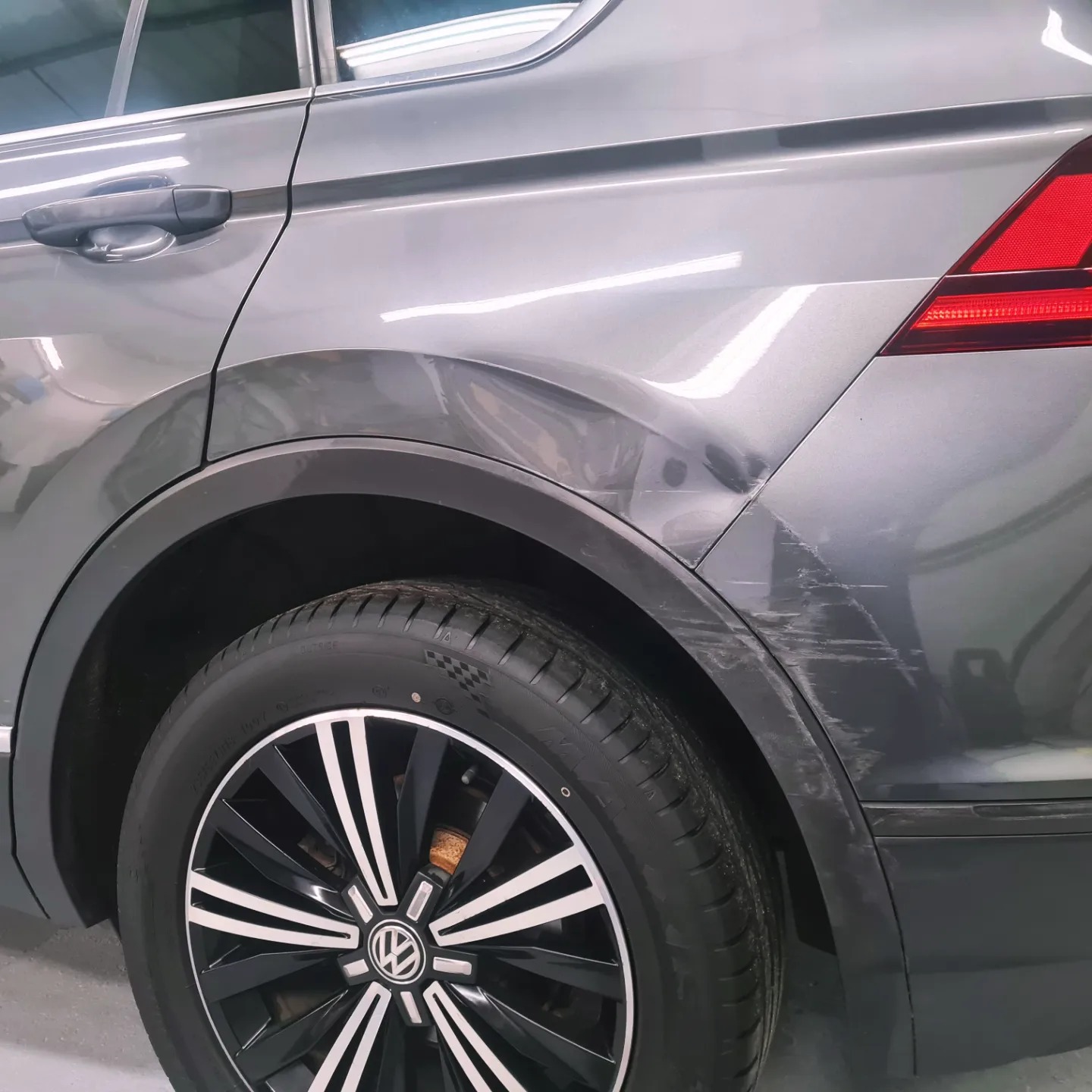 Grey VW Tiguan with a dented, scraped rear wheel arch and door