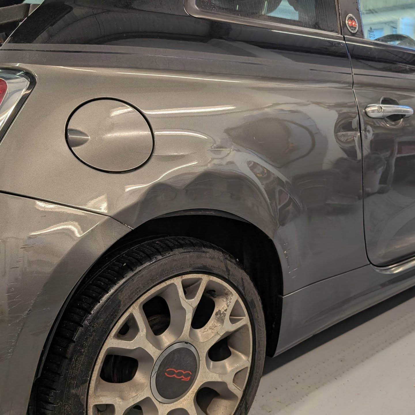 Grey Fiat 500 with a dent in the rear quarter by the fuel flap