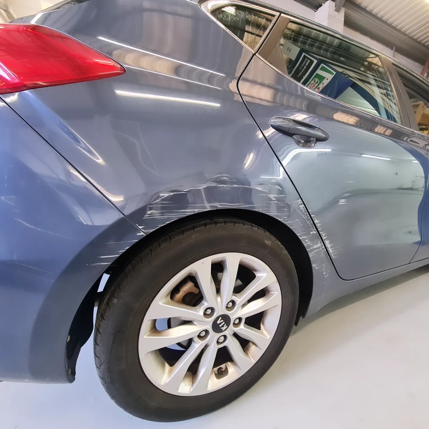 Grey Kia with scraped and dented rear door and arch